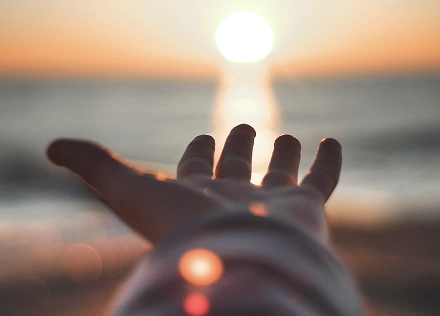 Hand reaching towards the sun, symbol of hope and healing